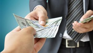 پورسانت فروش چیست؟ چند درصد است؟ احتمالا تاکنون اصطلاحاتی مانند پورسانت فروش یا حقوق پورسانتی به گوش شما خورده باشد. بسیاری از افراد در مواجهه با این واژه ها، پورسانت را به اشتباه معادل سود تجاری می دانند. اما آیا این برداشت صحیح است؟ در واقع، زمانی که می پرسیم پورسانت فروش چیست، باید بدانیم که این واژه به پاداش مالی اطلاق می شود که فرد بر اساس میزان فروش یا جذب مشتریان جدید دریافت می کند. در این مطلب از سایت امیر موحد، قصد داریم با نگاهی دقیق بررسی کنیم که پورسانت فروش چه مفهومی دارد و معمولا چه درصدی از مبلغ فروش به عنوان پورسانت تعیین می شود. پس اگر به دنبال درک بهتر این مفهوم کلیدی در دنیای بازاریابی و فروش هستید، توصیه می کنیم ادامه این مطلب را از دست ندهید. پورسانت فروش چیست؟ زمانی که فروشنده ای براساس میزان فروش خود مبلغی اضافه بر حقوق ثابت دریافت می کند، در حقیقت مشمول دریافت پورسانت فروش شده است. این شیوه پرداخت، به عنوان یکی از رایج ترین روش های ایجاد انگیزه در بین نیروهای فروش شناخته می شود و معمولا به منظور افزایش بهره وری و ترغیب به دستیابی به اهداف بالاتر مورد استفاده قرار می گیرد. در این ساختار، پورسانت به عنوان یک پاداش مستقل از حقوق پایه، به فروشنده تعلق می گیرد. به طور مثال، فرض کنید تیم فروش شرکت شما موفق شود دستگاهی به ارزش ۲۰۰ میلیون تومان به فروش برساند. طبق توافق اولیه که میان کارفرما و اعضای تیم فروش برقرار شده، درصدی از مبلغ فروش برای مثال ۲۰ میلیون تومان به عنوان پورسانت به آنان اختصاص می یابد. چنین سیستمی، نه تنها میزان تعهد و تلاش فروشندگان را افزایش می دهد، بلکه با ایجاد یک فضای رقابتی سالم، دستیابی به اهداف سازمانی را نیز تسهیل می کند. انواع پورسانت فروش چیست؟ کارفرمایان برای جبران زحمات نیروهای فروش، از شیوه های متنوعی جهت پرداخت پورسانت فروش بهره می برند. انتخاب ساختار مناسب، به نوع کسب وکار، اهداف فروش و سیاست های سازمان بستگی دارد. در ادامه به معرفی تعدادی از رایج ترین انواع پورسانت فروش می پردازیم که هر کدام نقش مهمی در ایجاد انگیزه و افزایش بهره وری تیم های فروش ایفا می کنند. پورسانت درآمد در برخی از سیستم های جبران خدمات، کارفرمایان با بهره گیری از ساختار پورسانت درآمد، علاوه بر پرداخت حقوق پایه، درصدی معین و توافق شده از میزان فروش را به فروشندگان اختصاص می دهند. این مدل پرداخت، همسو با اهداف سازمانی طراحی شده و به گونه ای تنظیم می شود که هم افزایش فروش و هم حفظ انگیزه نیروهای انسانی را در بلندمدت تضمین کند. پورسانت مستقیم در ساختار پورسانت مستقیم، فروشنده بدون دریافت حقوق پایه فعالیت می کند و کلیه درآمد وی مستقیما از محل فروش محصولات یا خدمات تامین می شود. در این شیوه، میزان دریافتی فرد به طور کامل وابسته به عملکرد فروش او بوده و هرچه حجم معاملات بالاتر باشد، سطح درآمد نیز افزایش می یابد. پورسانت مستقیم، با ایجاد پیوند مستقیم میان تلاش فروشنده و نتایج مالی، انگیزه قابل توجهی برای حداکثرسازی فروش فراهم می آورد و به عنوان یکی از مدل های پویای جبران خدمات در صنایع مختلف شناخته شده است. پورسانت مطلق در پورسانت مطلق، فروشندگانی که موفق به انجام فعالیت های معین همچون جذب مشتریان جدید یا تحقق اهداف تعیین شده می شوند، مشمول دریافت این نوع پاداش مالی می گردند. در این مدل، معیار پرداخت تنها به تحقق نتایج مشخص وابسته است و میزان پورسانت، مستقل از حجم کلی فروش تعیین خواهد شد. پورسانت مطلق، با تمرکز بر دستاوردهای کیفی و هدفمند، نقش مهمی در جهت دهی به رفتارهای استراتژیک فروشندگان ایفا کرده و سازمان را به سمت تحقق برنامه های کلان بازاریابی هدایت می کند. پورسانت پلکانی در این شیوه پرداخت، درصد پورسانت هنگام عبور فروشنده از سطوح معین فروش به صورت مرحله ای افزایش می یابد. نوع پلکانی معمولا برای افرادی طراحی شده که توانایی ثبت حجم های بالای فروش را در اختیار دارند. با هر جهش فروش به مرحله ای بالاتر، نرخ پورسانت تغییر کرده و انگیزه های تازه ای برای ادامه رشد ایجاد می شود. استفاده از این الگو، دستیابی به اهداف فروش و ارتقای سطح درآمد سازمان را به طرز قابل توجهی تسهیل می کند. پورسانت فروش چند درصد است؟ پورسانت فروش به میزان درصدی از مبلغ فروش محصولات یا خدمات اشاره دارد که به فرد فروشنده یا نماینده فروش به عنوان پاداش تعلق می گیرد. این مقدار به طور معمول به عنوان انگیزه ای برای افزایش فروش و عملکرد بهتر در نظر گرفته می شود. در صنایع مختلف، درصد پورسانت فروش ممکن است متفاوت باشد، اما به طور کلی میانگین آن بین ۲۰ تا ۳۰ درصد قرار دارد. عواملی همچون نوع صنعت، ساختار فروش و تجربه فرد بر مقدار دقیق این درصد تاثیرگذار است. به عبارت دیگر، در برخی شرایط، مانند سازمان های با مدل فروش خاص یا در بخش های با حجم بالای فروش، درصد پورسانت می تواند متفاوت از مقدار معمول باشد. شیوه محاسبه پورسانت فروش محاسبه پورسانت فروش یکی از جنبه های حیاتی در مدیریت تیم های فروش محسوب می شود که به دقت و شفافیت نیاز دارد. این فرآیند به طور معمول شامل چندین مرحله است که به شرح زیر می باشد. • تعیین زمان بندی پرداخت پورسانت فروش: ابتدا باید دوره زمانی که در آن پورسانت به فروشندگان تعلق می گیرد مشخص شود. این دوره می تواند ماهانه، فصلی یا به صورت توافقی دیگر باشد. در این مرحله، تعیین دقیق تاریخ پرداخت اهمیت ویژه ای دارد تا تمامی طرف ها از زمان دقیق و شرایط پرداخت مطلع باشند. • انتخاب ساختار پرداخت پورسانت: در این مرحله باید نوع ساختاری که بر اساس آن پورسانت به فروشندگان پرداخت می شود، مشخص گردد. ساختارها می توانند به صورت ثابت، متغیر یا ترکیبی از هر دو باشند. • اعمال متغیرهای موثر در محاسبه پورسانت: برخی از عوامل از جمله حجم فروش، نرخ موفقیت در فروش و حتی عوامل خاص بازار می توانند در میزان پورسانت تاثیر بگذارند. این متغیرها باید به دقت شناسایی شده و در محاسبه لحاظ شوند. • کسر بازده ها و هزینه های غیرمستقیم: در این گام، باید هزینه ها و بازده ها محاسبه شوند. برای مثال، اگر مشتریان بازگشتی داشته باشند یا محصول برگشتی باشد، پورسانت به نسبت کسر خواهد شد. • پرداخت پورسانت فروش به فروشنده: در نهایت، پس از طی مراحل فوق و محاسبه دقیق پورسانت، مبلغ نهایی به فروشنده پرداخت می شود. این پرداخت می تواند به صورت نقدی، امتیاز یا هر نوع دیگر از پرداخت ها صورت گیرد. چگونه ساختار پورسانت فروش را طراحی کنیم؟ پس از آن که با مفهوم پورسانت فروش آشنا شدید، مرحله بعدی طراحی یک ساختار مناسب برای پرداخت پورسانت است. این ساختار باید به گونه ای تنظیم شود که هم انگیزه های لازم را برای فروشندگان ایجاد کند و هم با اهداف استراتژیک سازمان هم راستا باشد. بررسی اهداف سالانه بررسی اهداف سالانه فروش به تعیین جهت گیری های استراتژیک کمک می کند و به فروشندگان راهنمایی می دهد تا مسیر فعالیت های خود را به درستی انتخاب کنند. این اهداف، با مشخص کردن استانداردها و معیارهای عملکرد، فروشندگان را قادر می سازند تا اولویت ها را شناسایی کرده و به صورت موثرتر به تحقق اهداف سازمانی بپردازند. بررسی بودجه و درآمد بررسی بودجه و درآمد در فرآیند فروش به تعیین چارچوب مالی برای تحقق اهداف استراتژیک کمک می کند. تخصیص دقیق منابع، شامل برنامه پورسانت، می تواند تاثیر مستقیمی بر نحوه اجرای استراتژی ها و کارایی تیم فروش داشته باشد. این تحلیل باید به طور دوره ای انجام شود تا هرگونه تغییرات در عملکرد یا نیازهای بازار، در بودجه و استراتژی های فروش لحاظ گردد. به اشتراک گذاشتن طرح پورسانت با دیگران به اشتراک گذاشتن طرح پورسانت با دیگران فرصتی برای دریافت بازخوردهای ارزشمند و شناسایی نقاط قوت و ضعف آن فراهم می آورد. این فرآیند می تواند به بهبود و تطبیق طرح با نیازهای مختلف سازمان کمک کند و در نهایت منجر به تغییرات مثبت در فرهنگ کاری و تاثیرات مالی گردد. جمع بندی در این مطلب به طور جامع بررسی شد که پورسانت فروش چیست و چگونه می تواند بر عملکرد تیم فروش تاثیر بگذارد. پورسانت فروش به عنوان درصدی از فروش، می تواند نقش مهمی در انگیزش و بهبود عملکرد فروشندگان ایفا کند. همچنین تیم فروش، به عنوان سرمایه ارزشمند هر کسب وکاری، با داشتن برنامه های پورسانت مناسب، قادر است اهداف تجاری را تحقق بخشد و موجب رشد و گسترش سازمان گردد. این رویکرد باعث می شود تا از نتایج حاصل، رضایت کامل به دست آید و کسب وکار به شکلی موثر توسعه یابد. در صورتی که تمایل دارید اطلاعات بیشتری در حوزه افزایش فروش و موفقیت کسب و کارتان به دست آورید، به شما شرکت در دوره DNA فروش ذهنی با امیر موحد را پیشنهاد می دهیم.